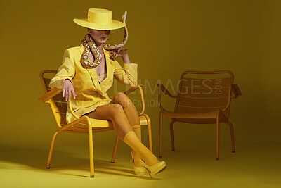 Buy stock photo Fashion, snake and woman in studio with art aesthetic for creative, colorful or trendy outfit. Confident, hat and female person with exotic animal for cool style and accessories by yellow background.