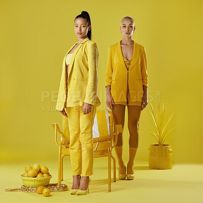 Buy stock photo Creative, portrait and women with yellow fashion, studio background or friends with makeup for glow. Fruit, aesthetic and people with stylish clothes, confident and serious with colorful outfit