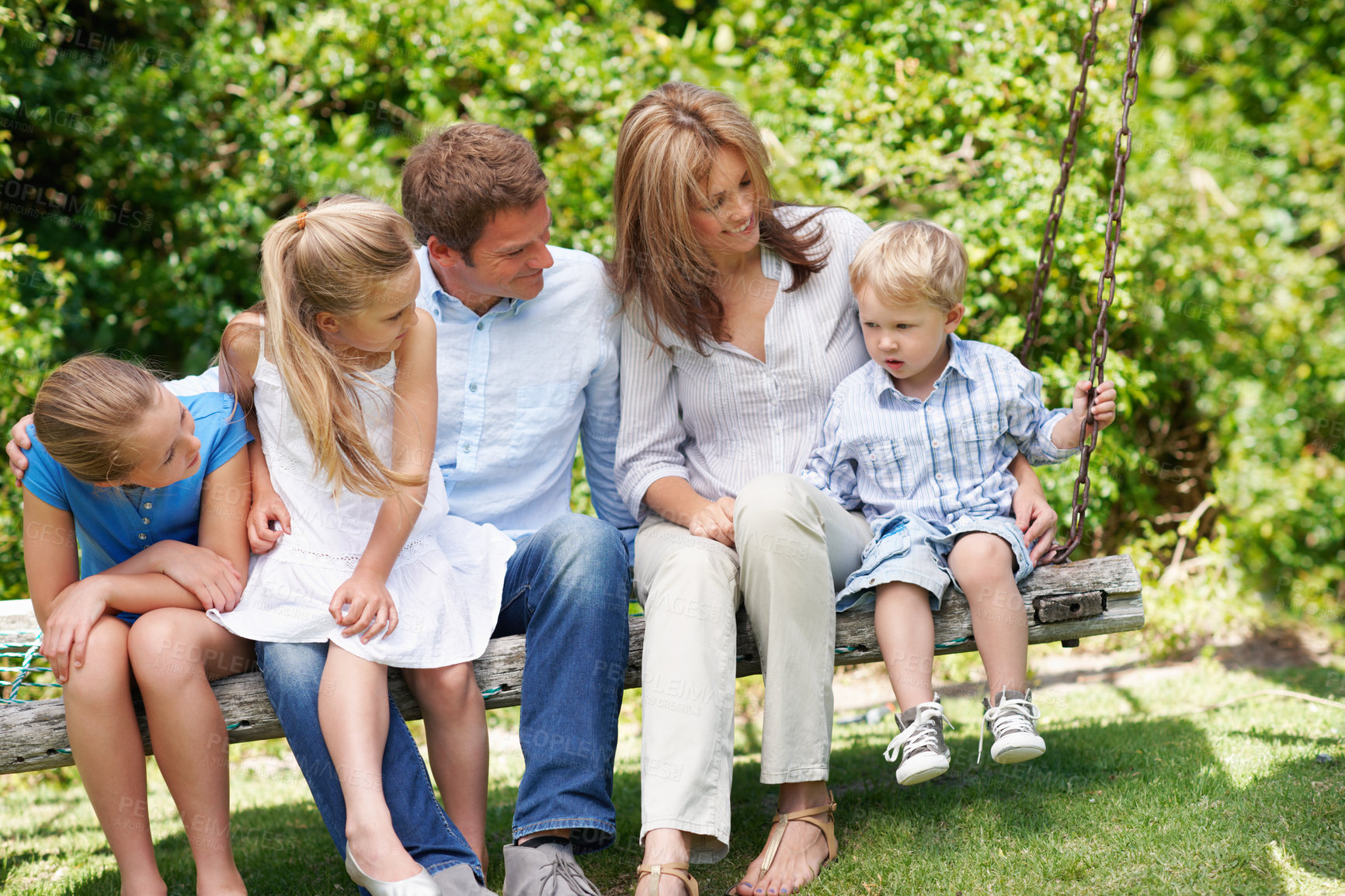 Buy stock photo Relax, parents and children with smile on bench for bonding together, holiday break and relationship. Love, happy people and kids at park for family outing, summer weekend and connection with support