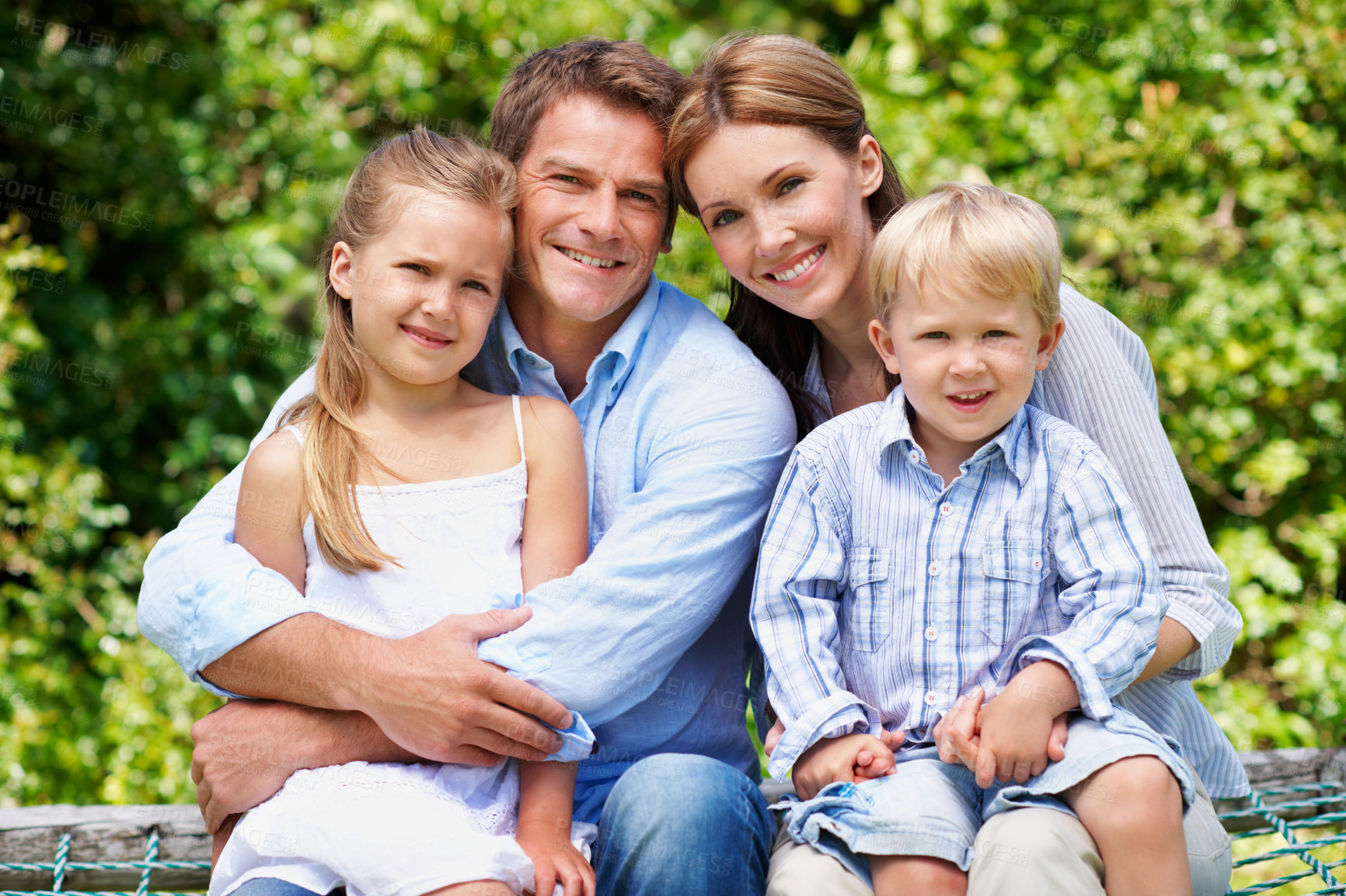 Buy stock photo Smile, parents and relax with kids at park for love, affection and bonding on holiday trip. Portrait, people and bench with children for support, family connection and vacation getaway in countryside