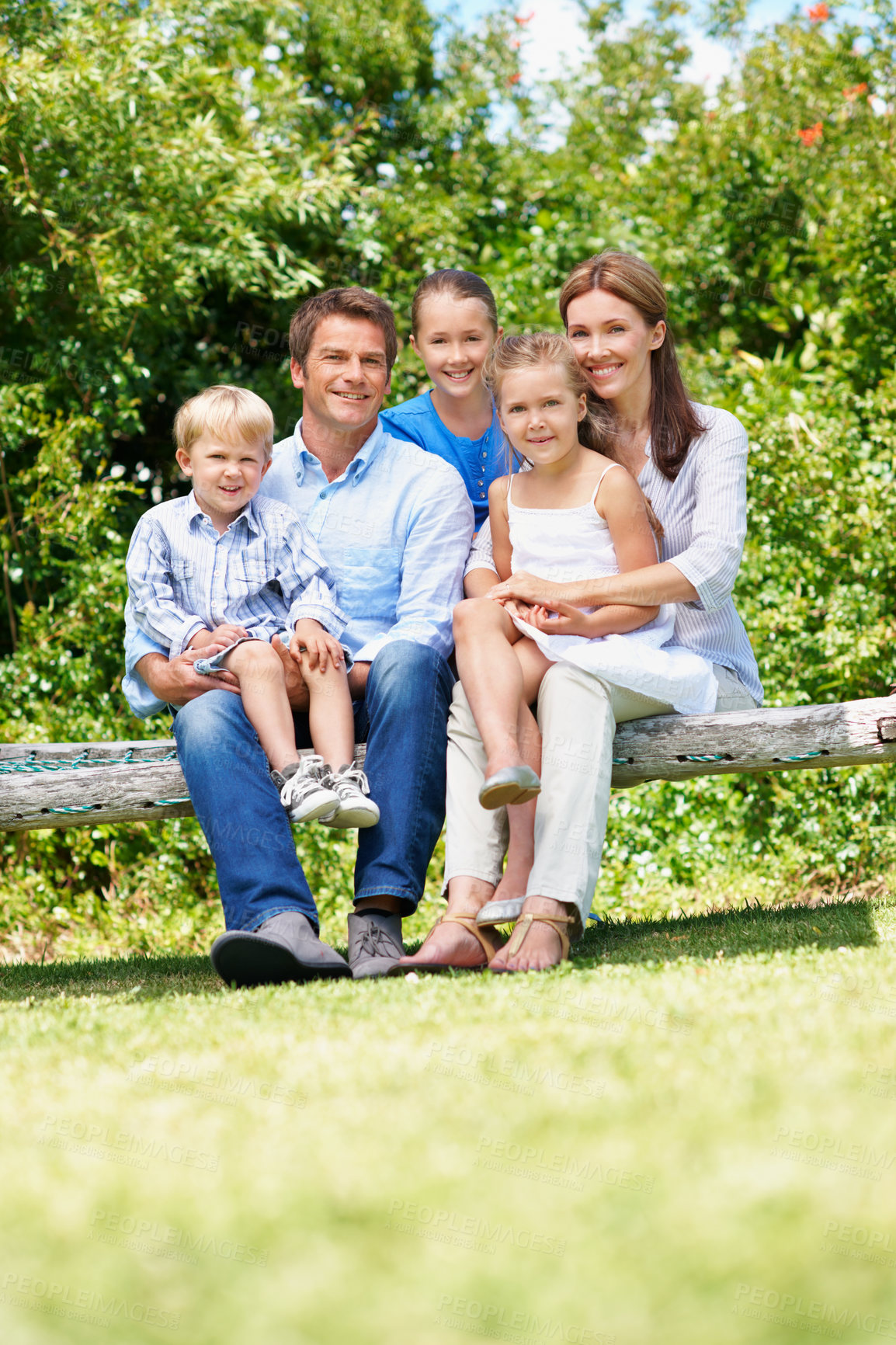 Buy stock photo Happy, parents and relax with kids at park for love, affection and bonding on holiday trip. Portrait, people and bench with children for support, family connection and vacation getaway in countryside