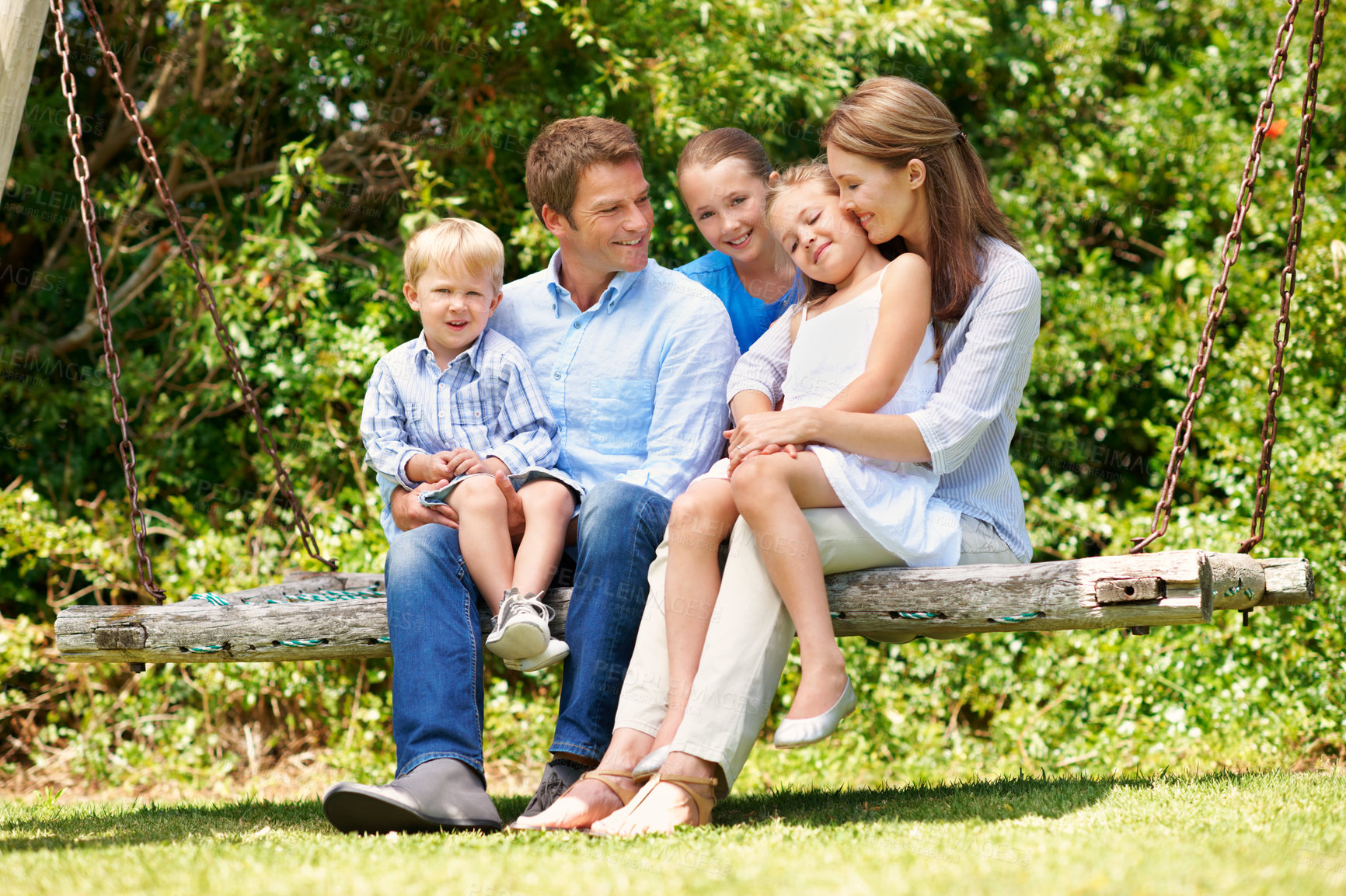 Buy stock photo Relax, smile and summer with family on swing together for bonding, love or support. Backyard, portrait or security with mom, dad and sibling children outdoor in garden for break, connection or growth
