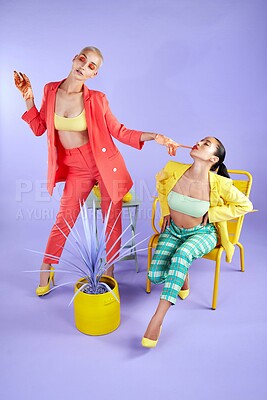 Buy stock photo Fashion, friends and women with chair in studio, artistic style and bold cosmetics for retro aesthetic. Creative, bite glove and people with trendy wardrobe, vibrant makeup and purple background