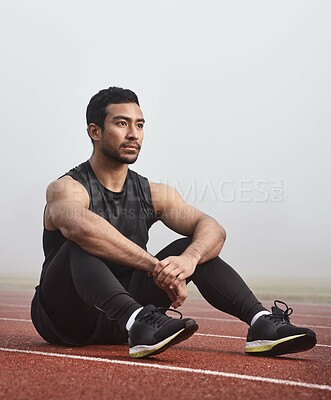 Buy stock photo Thinking, track and man on floor with race or training idea for sports in mist or fog. Confident, fitness and athlete or runner for competition, tournament and wellness strategy for outdoor workout