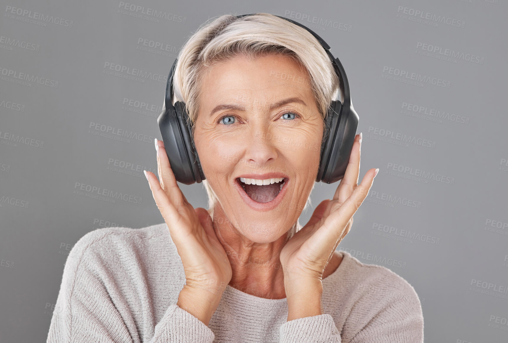 Buy stock photo Portrait, headphones and mature woman in studio with smile for sound, music or listening experience. Happiness, excited and person with wow for audio quality, podcast or news on gray background
