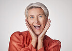 Portrait of one beautiful caucasian mature woman isolated against a grey studio background and expressing  shock. Senior woman making facial expressions and looking surprised
