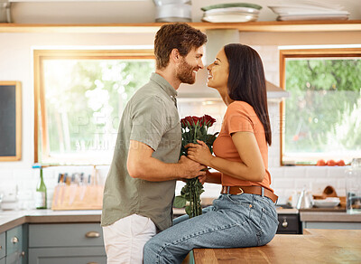 Buy stock photo Smile, couple and love with flowers in kitchen for care, partner appreciation and anniversary gift. Happy, people and roses for celebration, gratitude and romantic present on special occasion in home