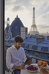 Travel man using digital tablet technology view Eiffel Tower Paris hotel terrace breakfast destination vacation