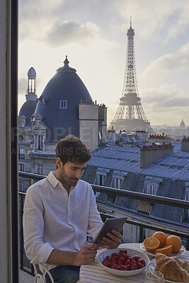 Buy stock photo Breakfast, Eiffel Tower and tablet with man on balcony of hotel for holiday, travel or vacation. App, food and landmark with tourist on terrace of accommodation for sightseeing in Paris, France