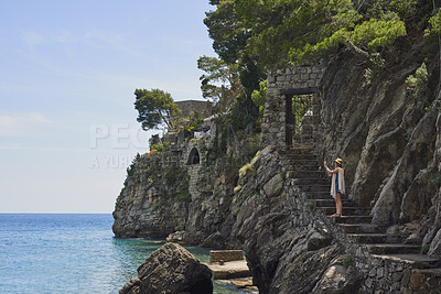 Buy stock photo Woman, travel and phone for photography by ocean, adventure and steps for coastal memory. Mobile app, tourism and person with sightseeing, trip and seaside staircase with taking picture outdoor
