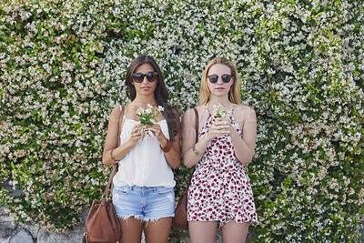 Buy stock photo Friends, holiday and sunglasses on summer fashion with flowers, bonding together or outfit on weekend. Women, floral plants and jasmine bush on travel outdoor, trendy clothes and shades for vacation.
