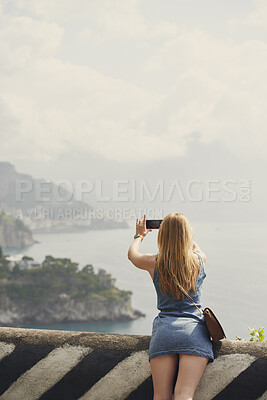 Buy stock photo Travel, photography and back of woman outdoor on holiday, getaway or weekend trip on coast. Mockup space, adventure and female person with picture for memory, social media or blog for tourism tips.
