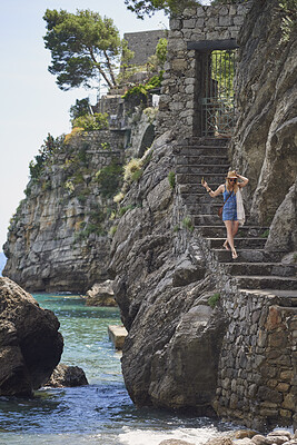 Buy stock photo Woman, travel and explore on steps by ocean, adventure and freedom with coastal experience. Walking, tourism and female person with sightseeing, trip and seaside staircase with journey in Italy