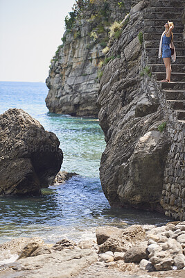 Buy stock photo Woman, travel and peace on steps by ocean, adventure and enjoy nature with coastal experience. Calm, tourism and female person on beach, stress relief and seaside staircase with freedom in Italy
