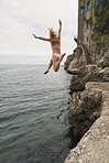 Beautiful girl  jumping into ocean having excitement freedom fun action healthy travel vacation adventure
