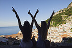 Beautiful happy tourist girl friends enjoying scenic view arms raised of Amalfi Coast on summer adventure vacation