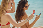 Beautiful girl friends using smart phone technology communication sharing on paradise beach destination summer wanderlust vacation