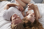Beautiful man woman couple lying in bed cuddling playful biting together in love lifestyle relationship overhead