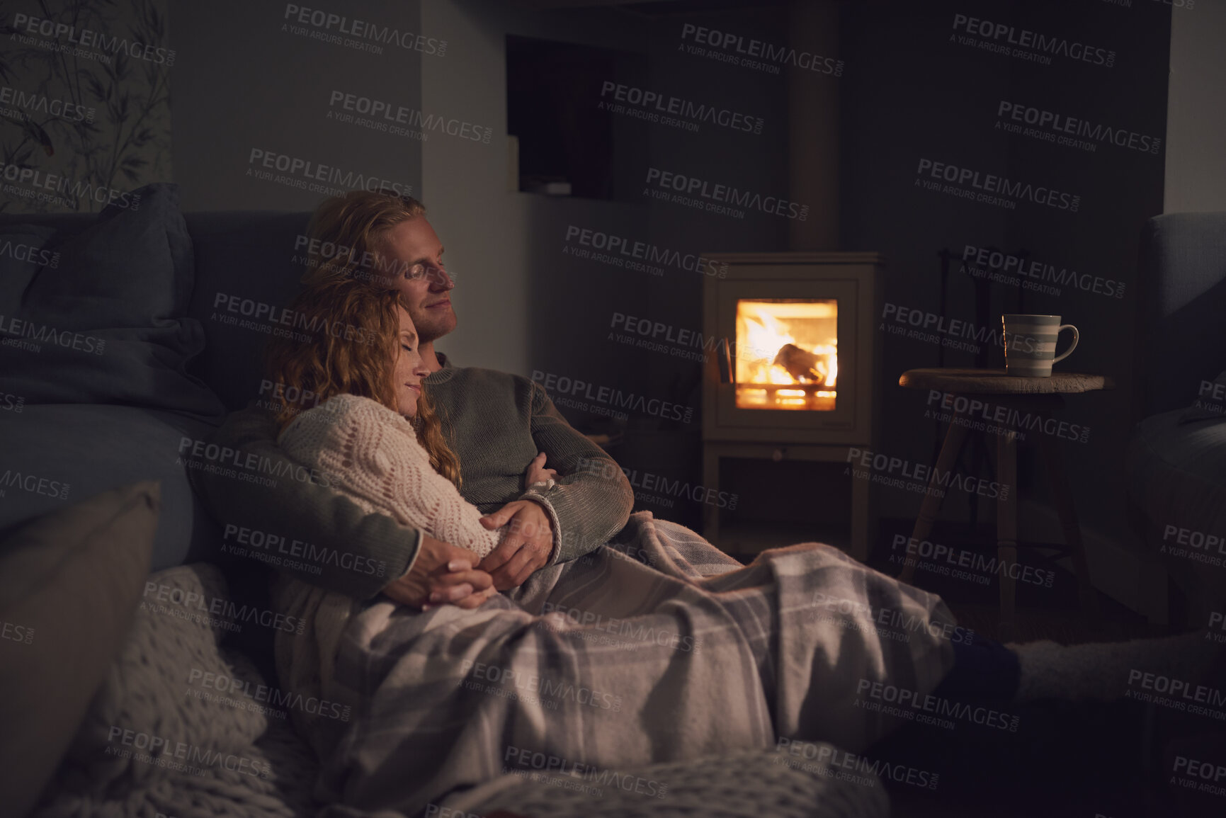 Buy stock photo Couple, relax and cuddle with blanket in living room, comfortable and bonding with partner on break. Love, home and embrace with spouse at night, commitment and happy people with fireplace in lounge
