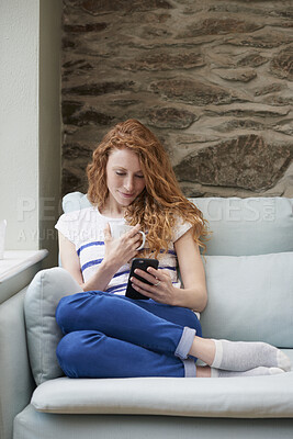 Buy stock photo Phone, message and woman with coffee in lounge, online or communication with contact on social media. Relax, home and happy person with mobile for chat, reading and chilling with beverage in house