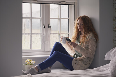 Buy stock photo Coffee, phone and typing with woman at window in home for browsing, social media or texting. App, drink and relax with calm person in apartment for morning break, reading or weekend connection