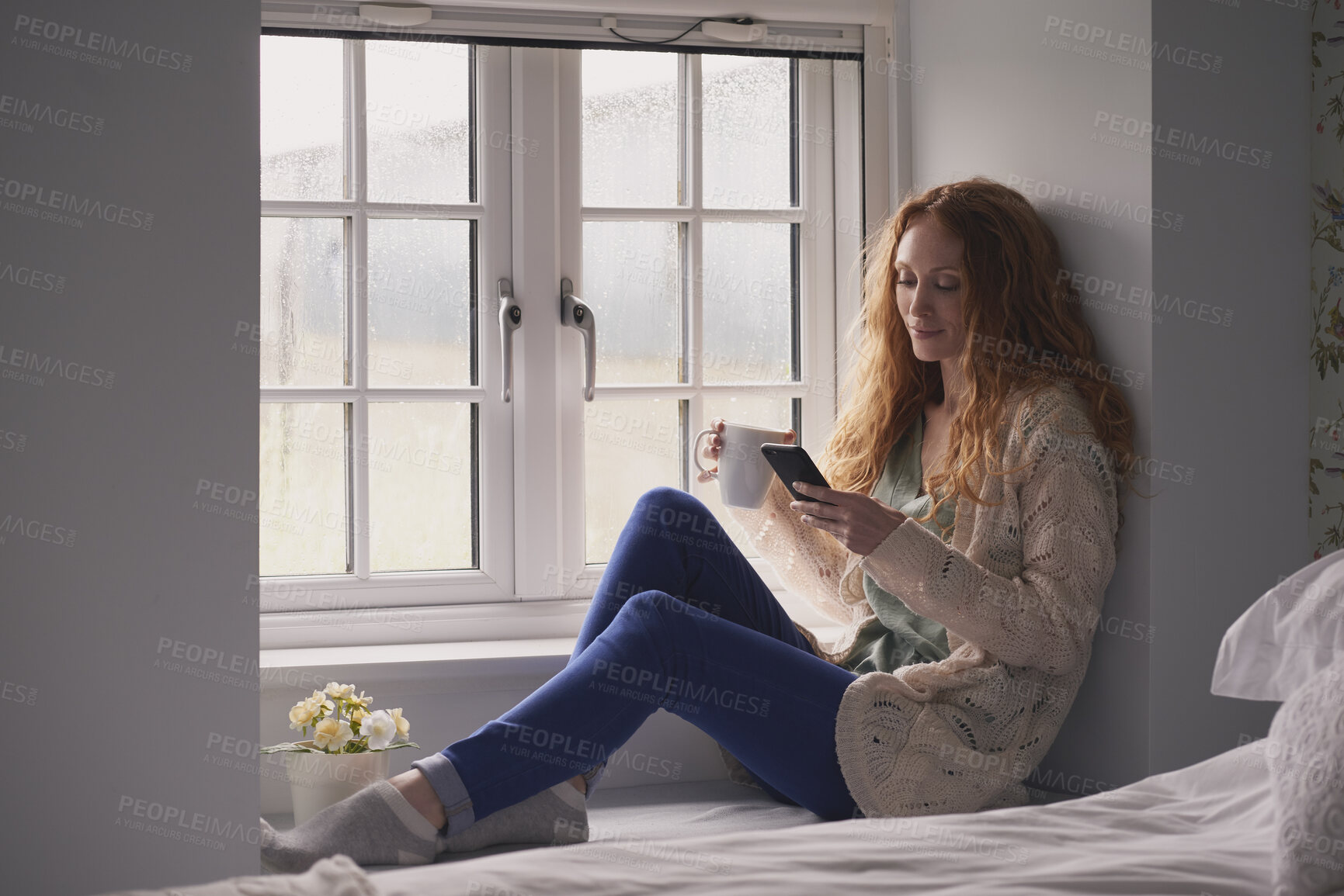 Buy stock photo Coffee, phone and typing with woman at window in home for browsing, social media or texting. App, drink and relax with calm person in apartment for morning break, reading or weekend connection