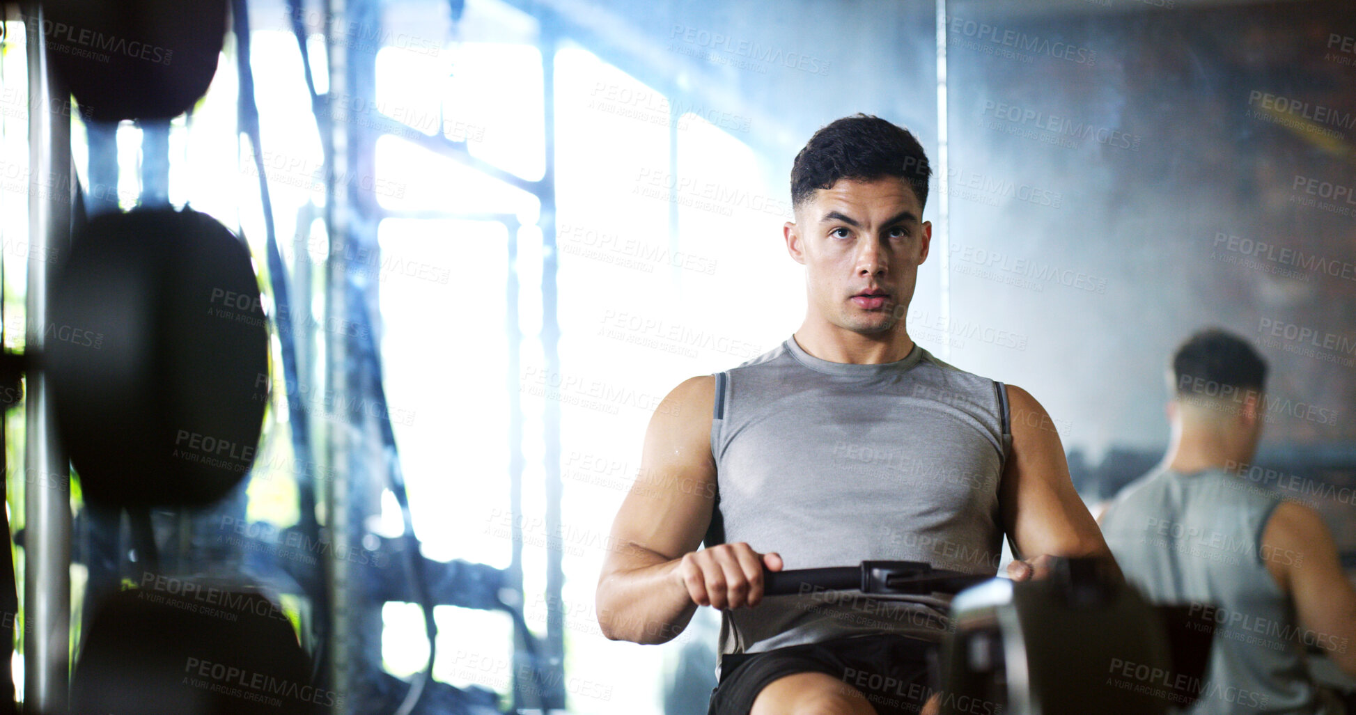 Buy stock photo Fitness, training or man in gym with rowing, power cardio or strength exercise for body improvement. Serious, endurance or athlete with machine, core workout or challenge for muscle development.