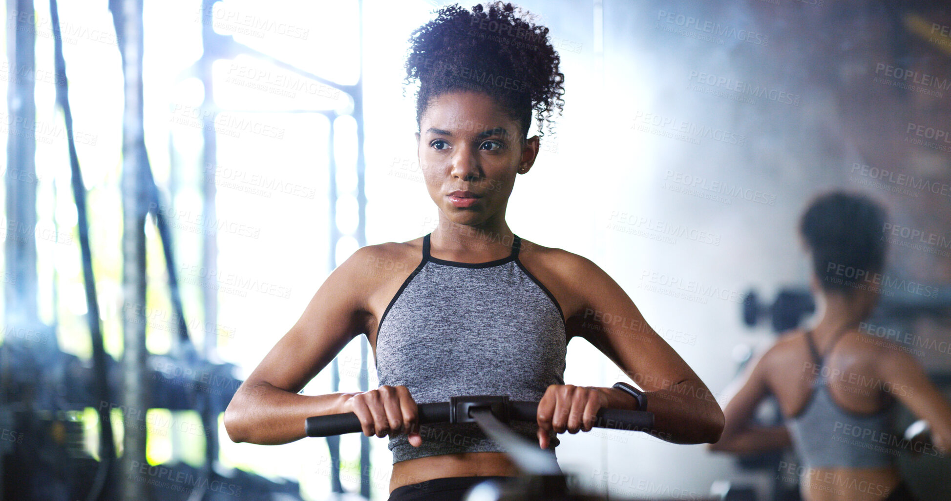 Buy stock photo Fitness, training or woman in gym with rowing, cardio or strength exercise for body improvement. Serious, endurance or African person with machine, core workout or challenge for muscle development.