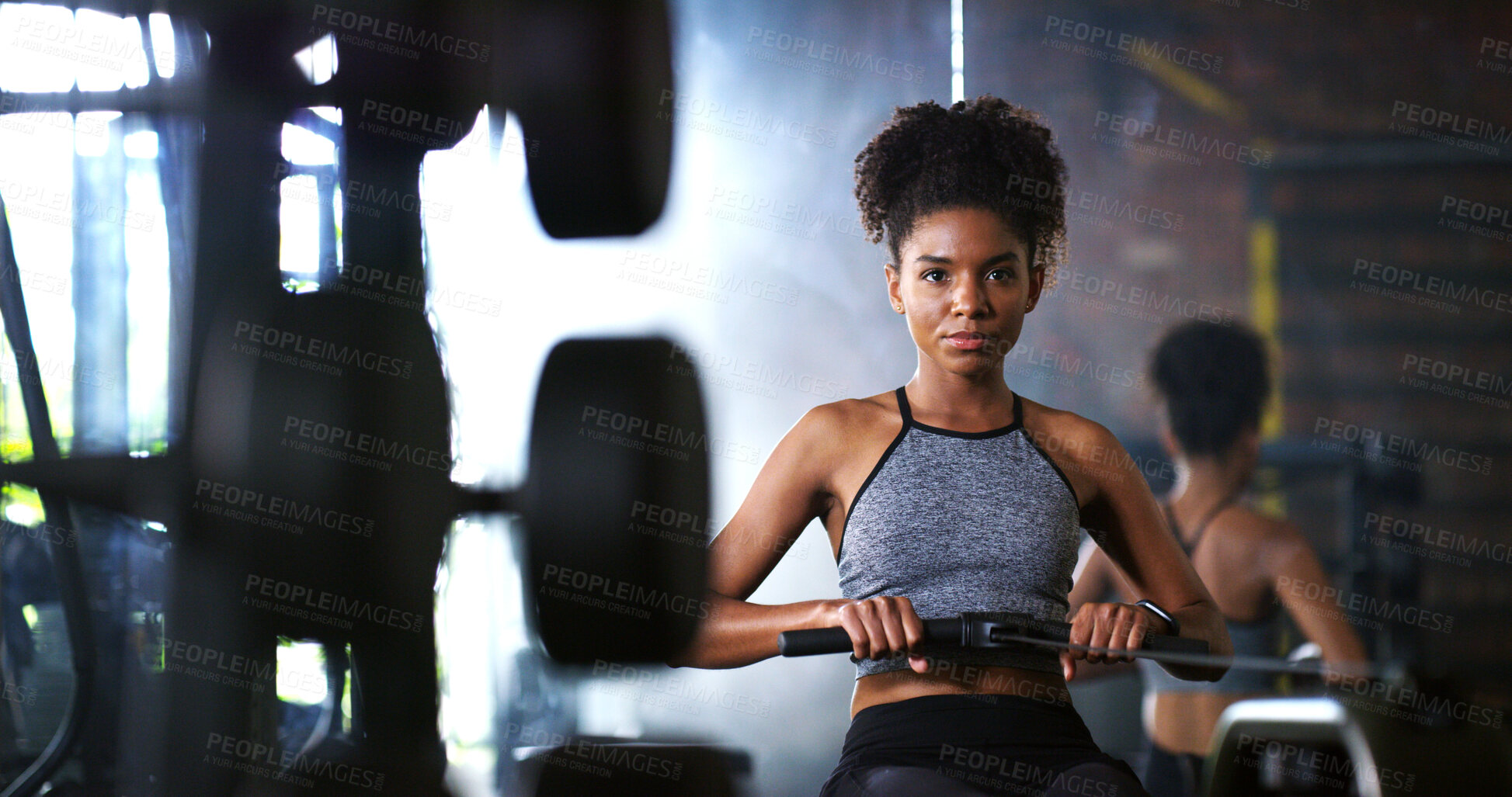 Buy stock photo Fitness, training or athlete in gym with rowing, power or strength exercise for body improvement. Serious, endurance or African woman with machine, core workout or challenge for muscle development.