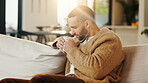 Sniffing, coffee and man on couch in home, chilling or comfortable on weekend with caffeine beverage. Fresh, scent and person with tea on peaceful break, aroma and relax with hot drink in lounge