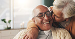 Old couple and bonding with kiss in house, retirement and laughing with partner on weekend or relax. Elderly people, embrace and comfortable with spouse, romance and affection with smile in lounge