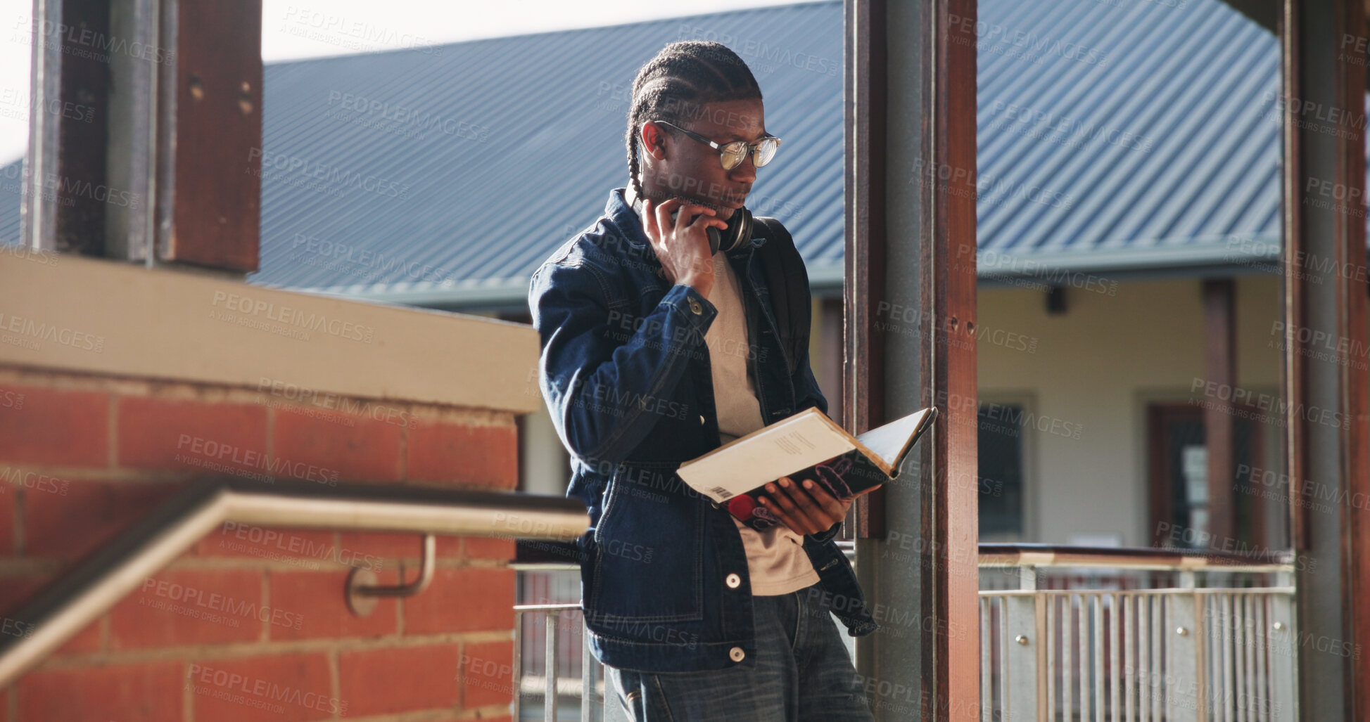 Buy stock photo Headphones, reading and black man with book at university for education, learning and review for test. Scholarship, student and study notes with paper at campus for exam, information and knowledge