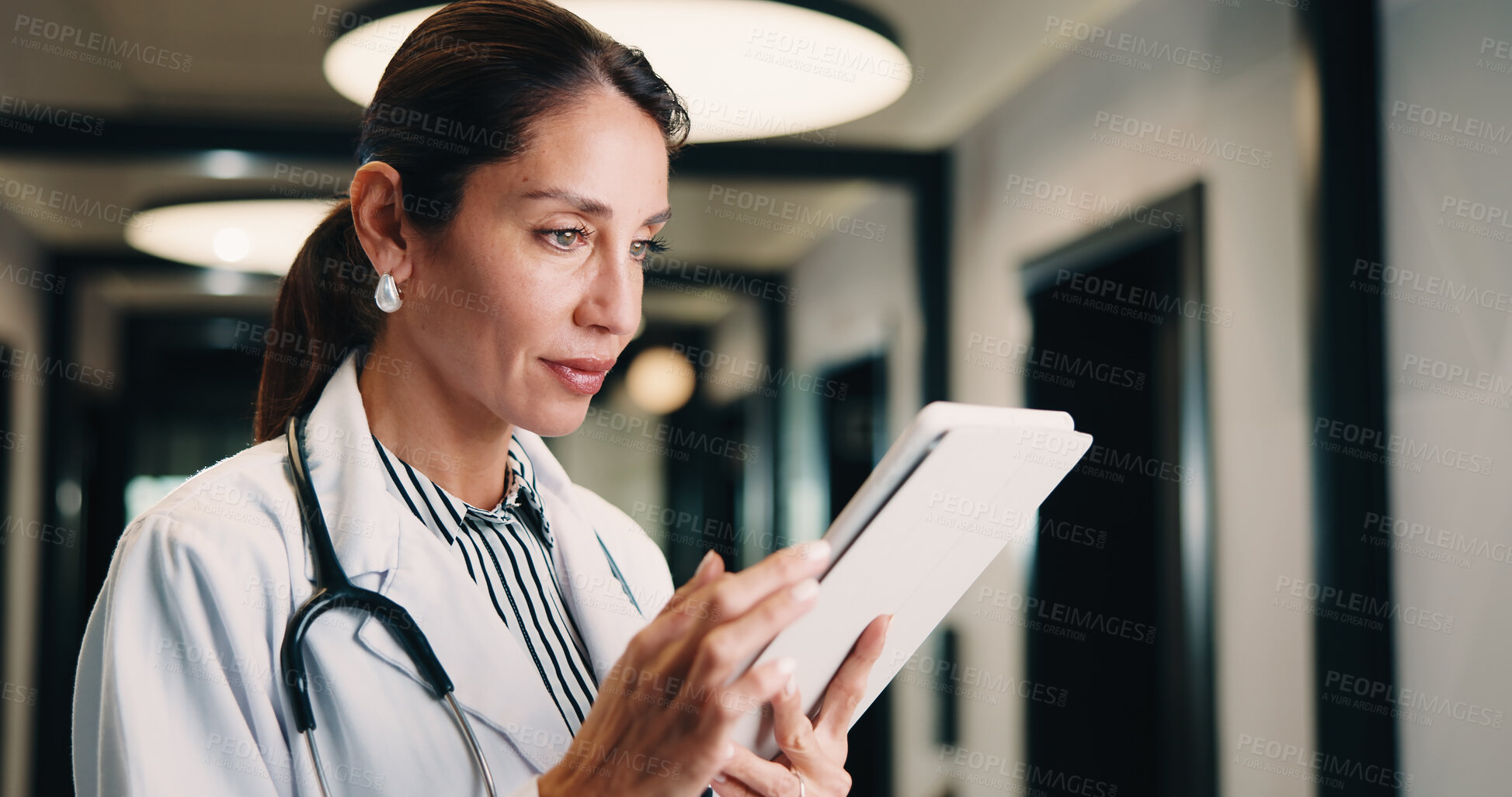 Buy stock photo Hospital, tablet and doctor with digital records, schedule or healthcare app for research. Clinic, tech and physician woman with telehealth report, review or reading of online results in hallway