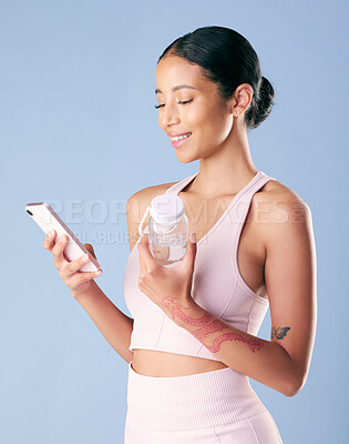 Buy stock photo Phone, smile and woman in studio for exercise, membership application or online app. Fitness, water bottle and gym person with tech for networking, wellness contact or social media on blue background