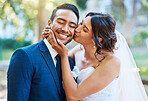 Beautiful bride kissing her groom on the cheek. Happy loving newlyweds enjoying romantic moments on their wedding day in nature