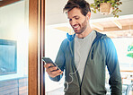 One fit young caucasian man listening to music with earphones from a cellphone while taking a break from exercise at home. Guy texting and using fitness apps online while browsing social media and watching workout tutorials