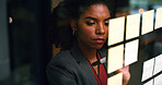 Night, writing and black woman at glass wall with sticky note, brainstorming or plan for audit deadline. Space, auditor and businessperson work late in office with strategy, problem solving and idea.