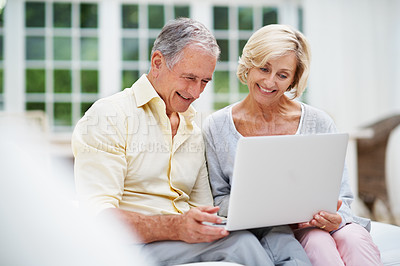 Buy stock photo A delighted senior couple chatting online to their family in the lounge