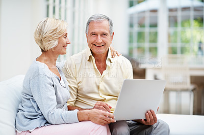 Buy stock photo A senior man using a laptop with his wife in their lounge