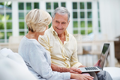 Buy stock photo A senior man looking into his wife's eyes as they use a laptop in their lounge