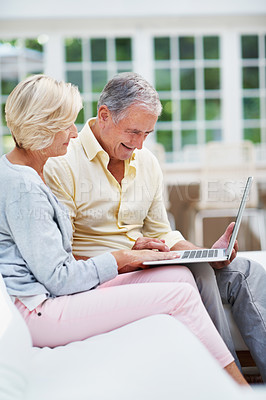 Buy stock photo A delighted senior couple using a laptop while relaxing in their lounge