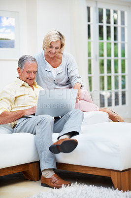 Buy stock photo A senior couple browsing the internet on their laptop while relaxing in the lounge