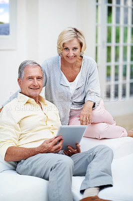 Buy stock photo Portrait of a senior couple using a tablet while relaxing in their lounge