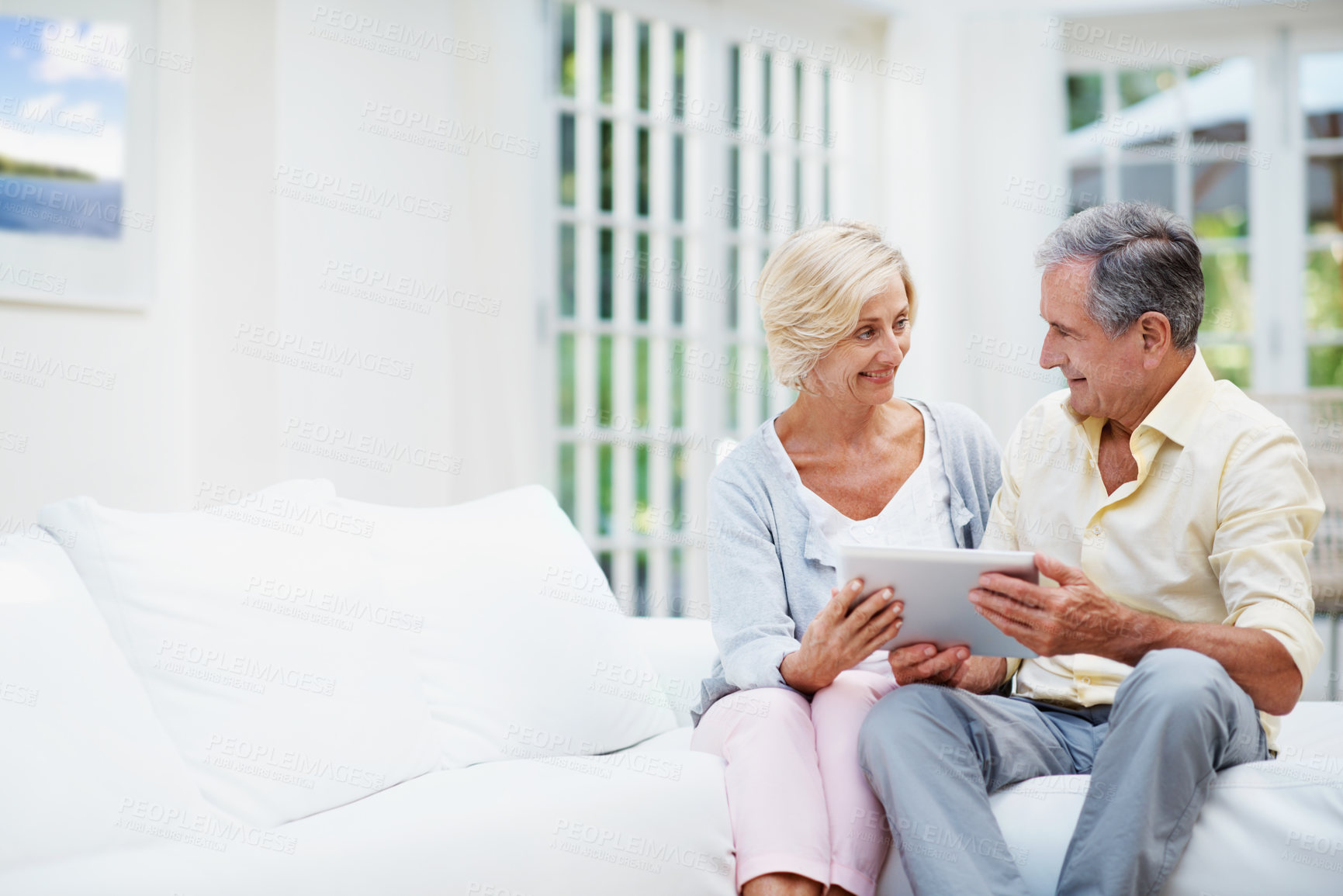 Buy stock photo Smile, tablet and love with old couple on sofa for retirement home review, planning and support. Senior living research, discussion and connection with elderly man and woman in lounge space of house