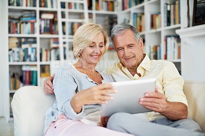 Buy stock photo A senior couple reading an ebook together in their study at home