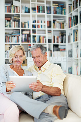 Buy stock photo A senior couple reading an ebook together in their study at home