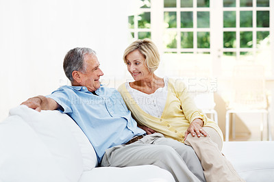 Buy stock photo A senior couple sitting together in their living room while looking at each other