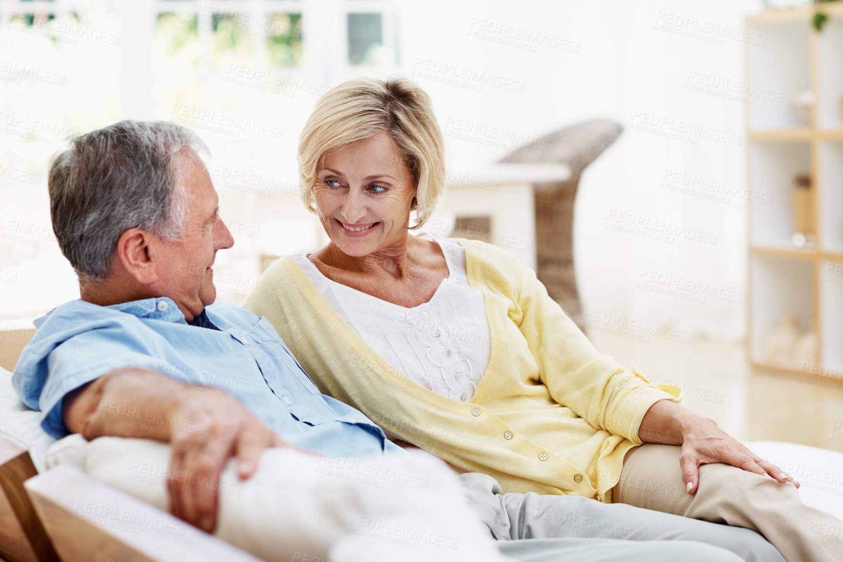 Buy stock photo Senior, happy couple and relax with talk in home for bonding, marriage security and wellness. Pensioner, people and conversation on sofa for retirement support, connection and loyalty in living room
