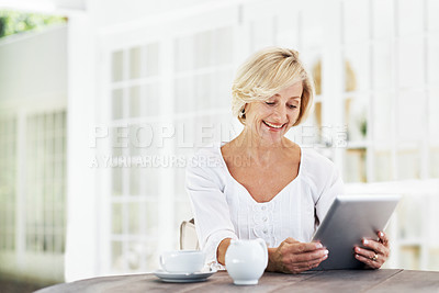 Buy stock photo A smiling senior woman holding a digital tablet while sitting outside with a cup of coffee - copyspace