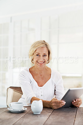 Buy stock photo A smiling senior woman holding a digital tablet while sitting outside with a cup of coffee  - portrait